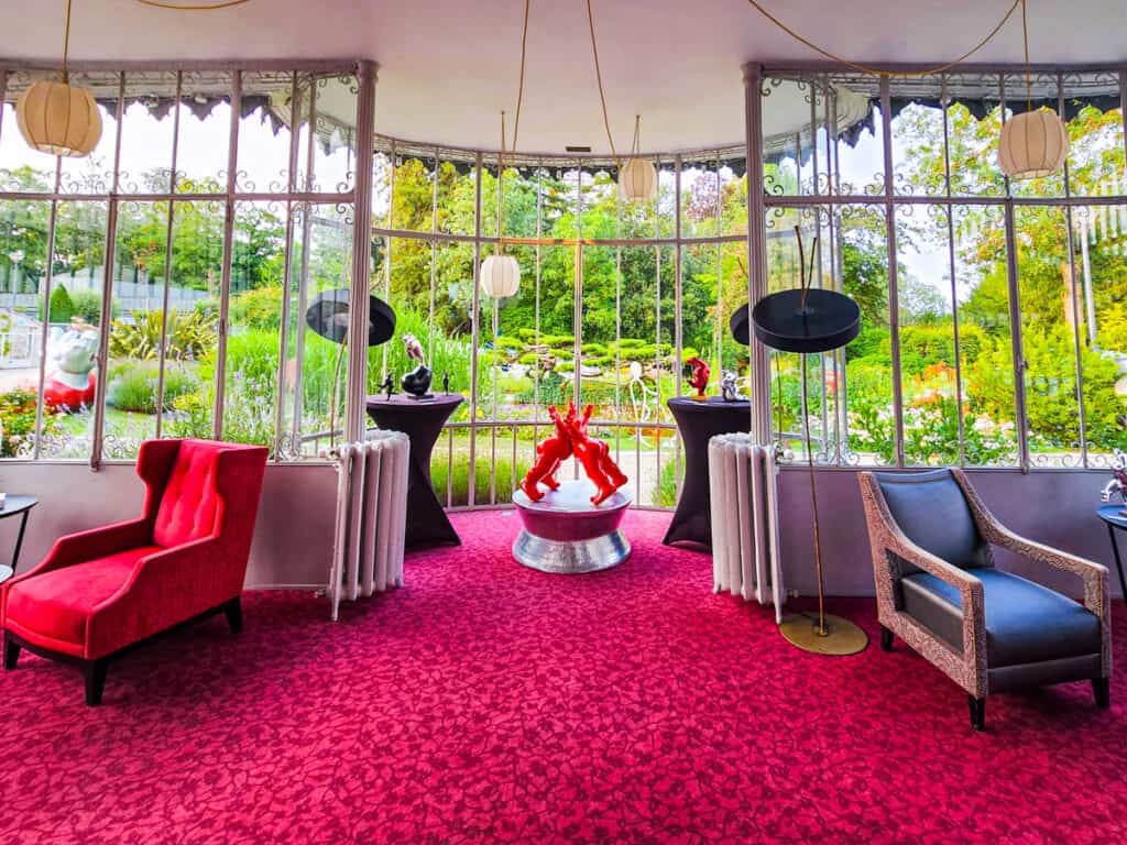 red carpeted room with glass windows looking out to a gardens