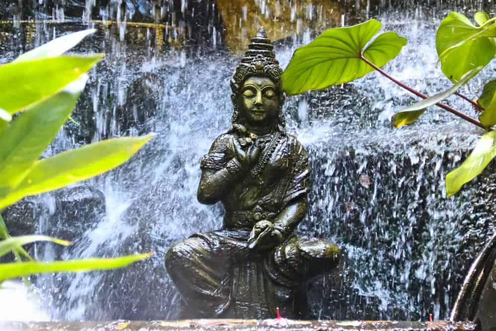 buddha statue in front of waterfall