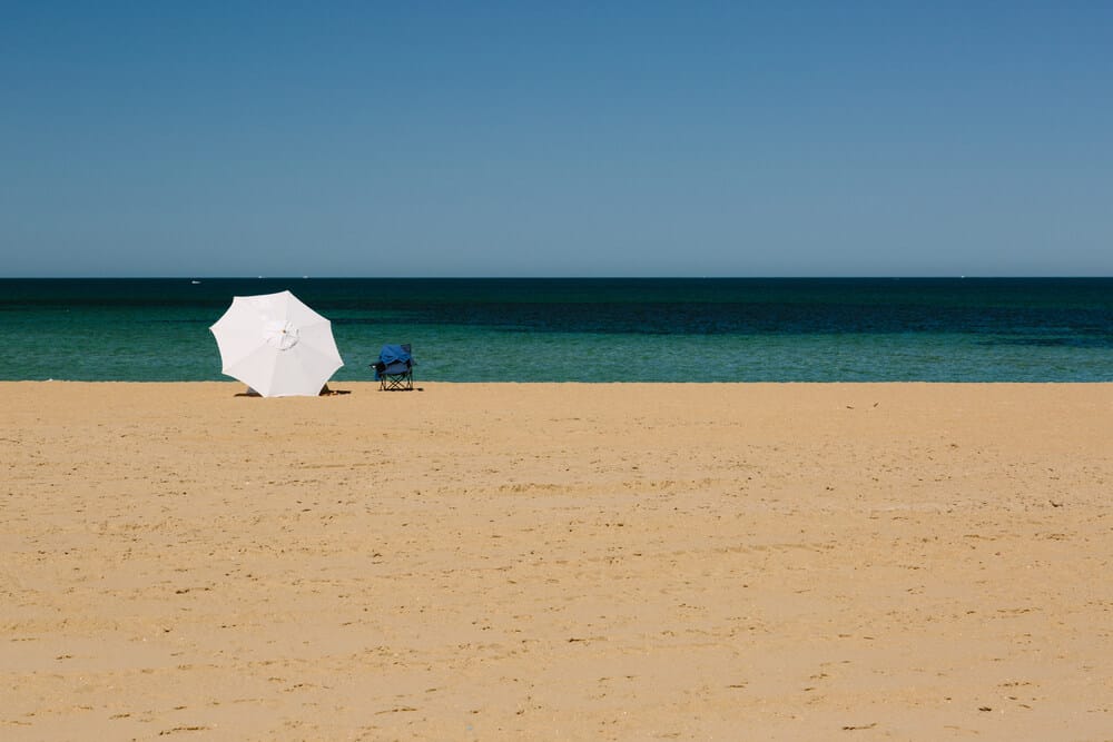 white umbrella and chair on Mordialloc Beach Melbourne