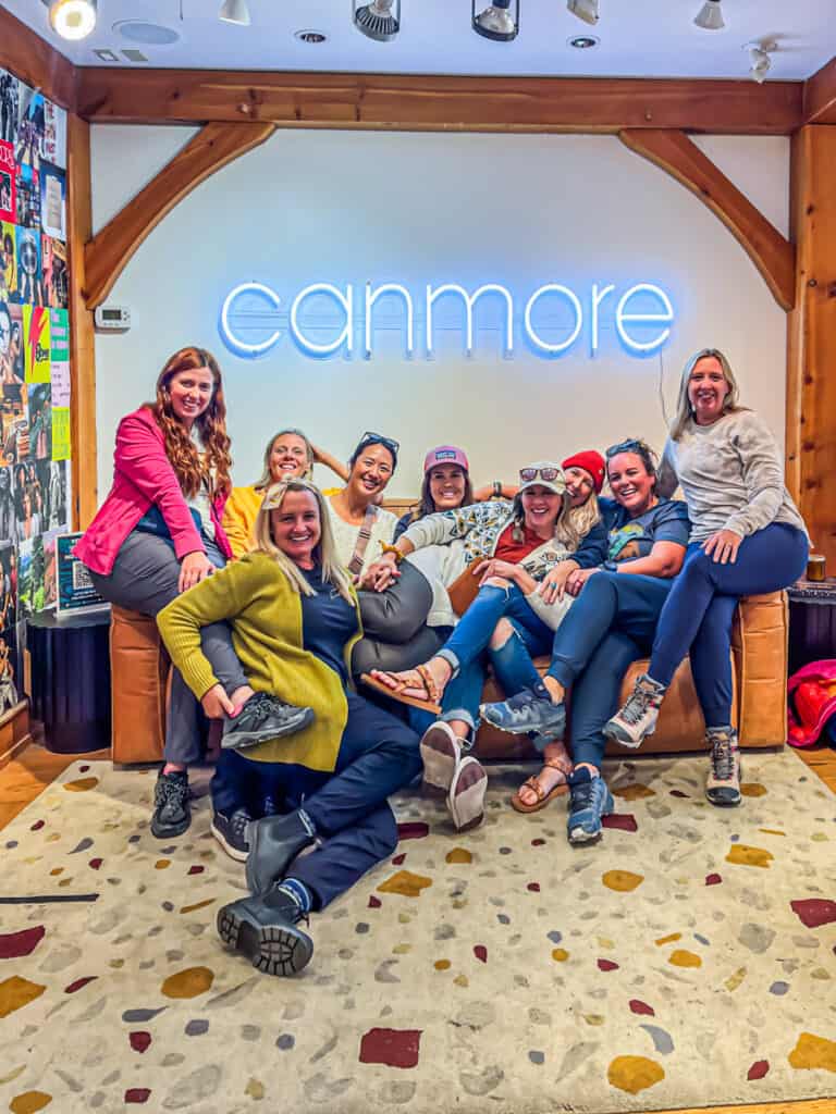 group of women sitting under Canmore sign