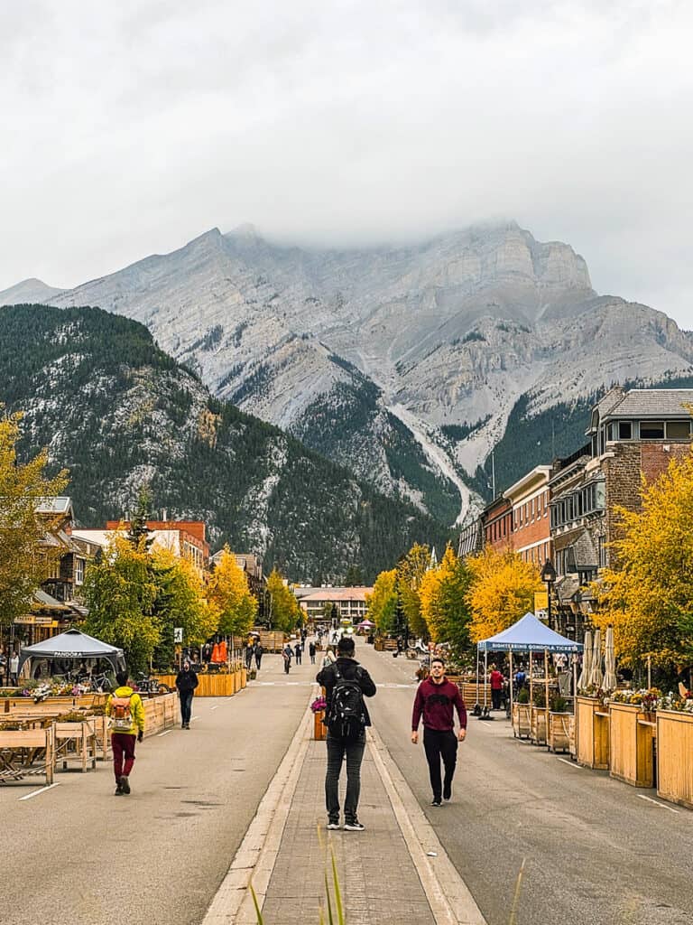 people walking down main street f banff with mountain at the end
