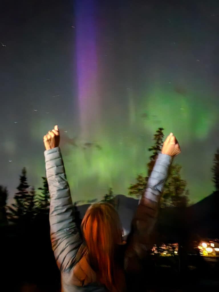 caz holding up arms looking at northern lights