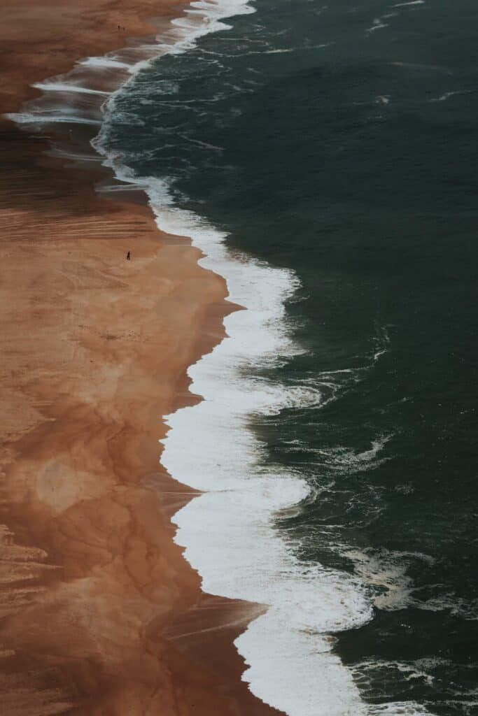waves crashing to shore on golden beach Praia da Nazaré
