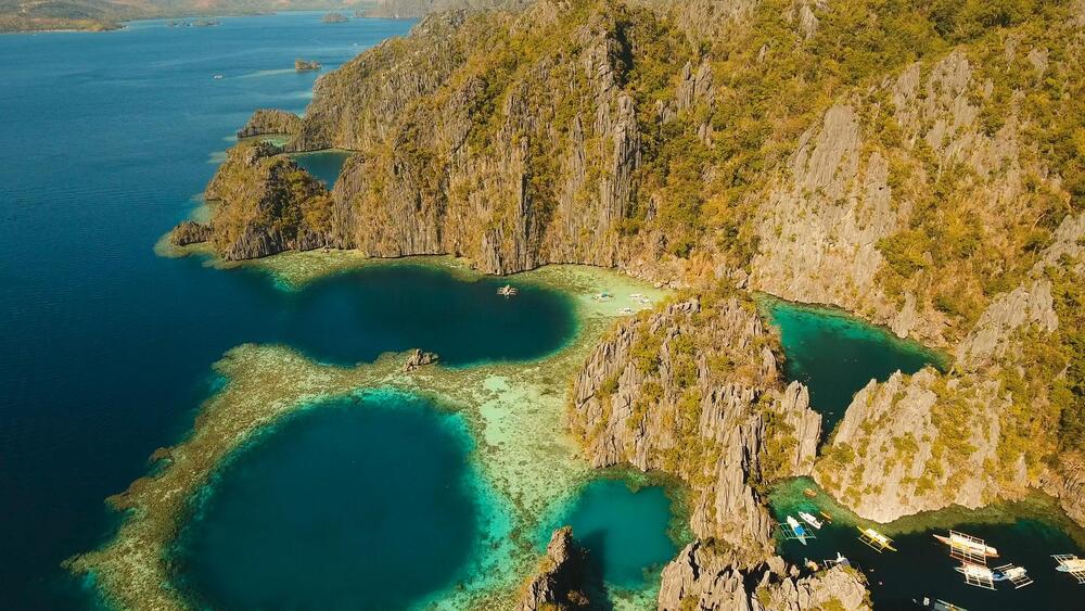 Aerial view: Twin Lagoon with blue, azure water in the middle of small islands and rocks. Beach, tropical island, sea bay and lagoon, mountains with forest, 