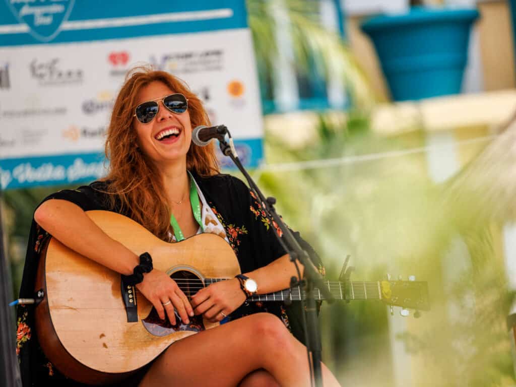 girl on stage with guitar laughing