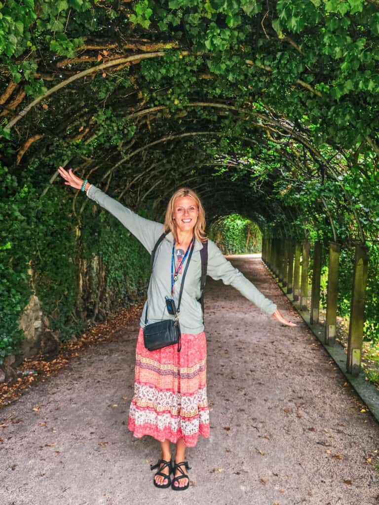 lady with arms outstretched in tunnel of greenery