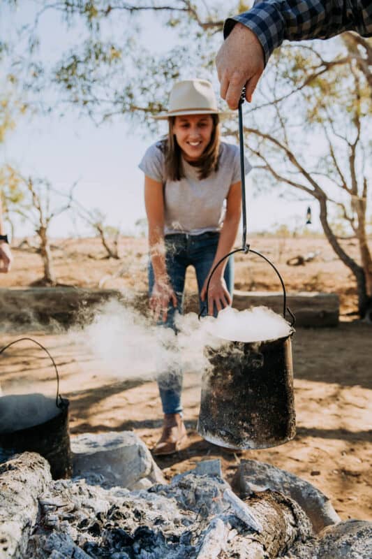 woman looking at billy cooking over campfire