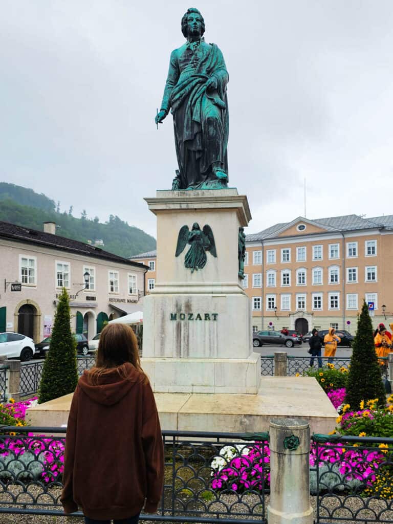 girl looking at statue of mozart in square in salzburg
