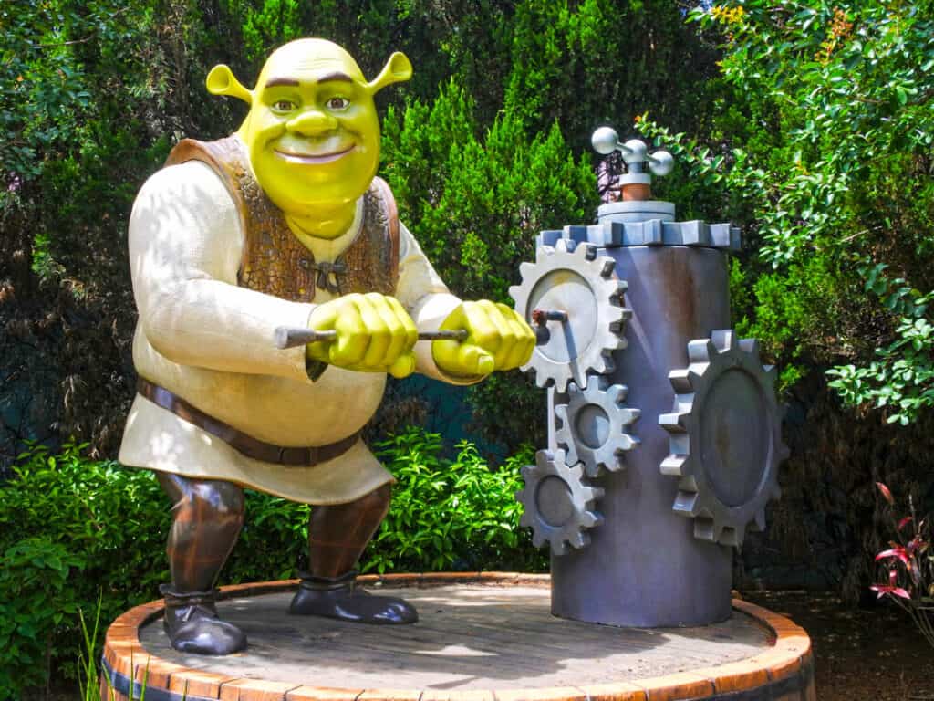 Shrek character turning a chainwheel of old hand water pump 