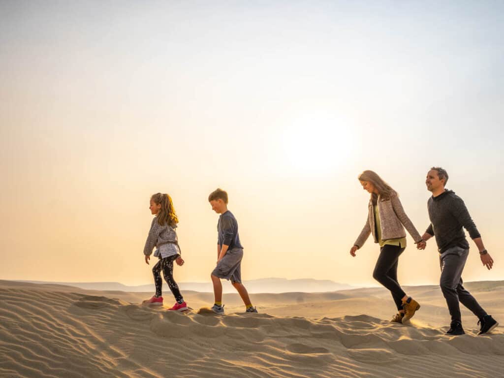 family walking on sand dunes