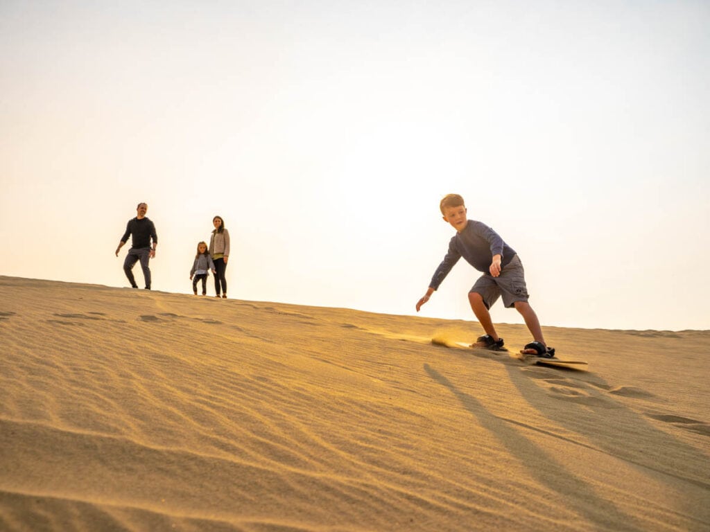 family sandboarding down killpecker sand dunes wyoming