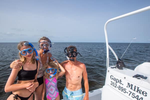 Family of four wearing snorkels on a boat.