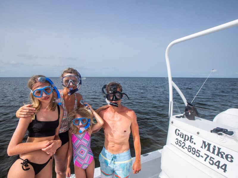 Family of four wearing snorkels on a boat.