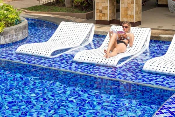 woman sitting on a lounge chair next to a pool