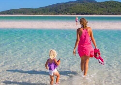 woman and child walking in the shallow waters of Whitehaven Beach