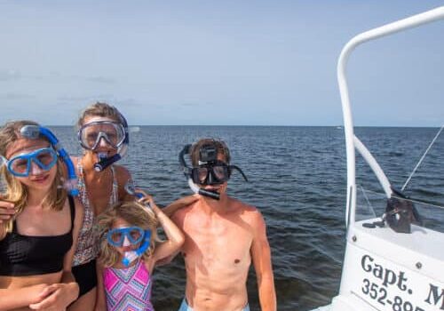 Family of four wearing snorkels on a boat.