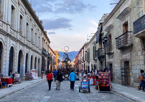 People walking down a street in Oaxaca, Mexico surrounded by buildings